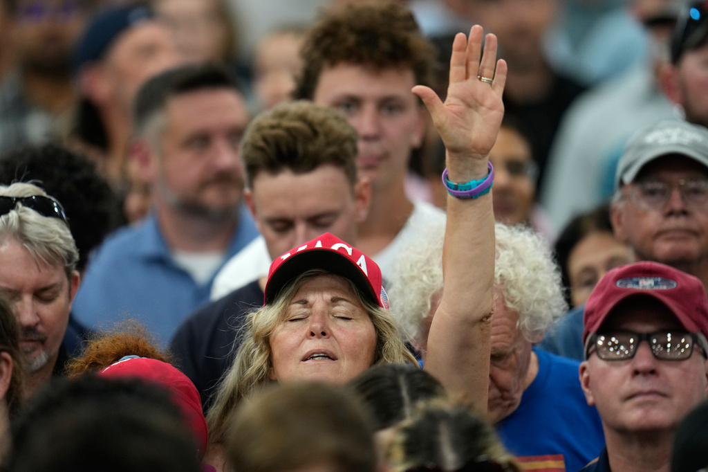 People pray before President Donald Trump speaks during an event at the General Motors Proving Ground Monday, July 27, 2026, in Milford, Mich. (AP Photo/Paul Sancya)