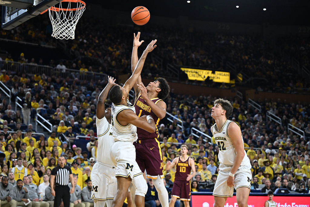 Minnesota guard Isaac Asuma (1) shoots the ball over Michigan guard Nimari Burnett (4) and Michigan guard L.J. Cason (2) in the first half of an NCAA college basketball game in Ann Arbor, Mich., Tuesday, Feb. 24, 2026. (AP Photo/Lon Horwedel)
