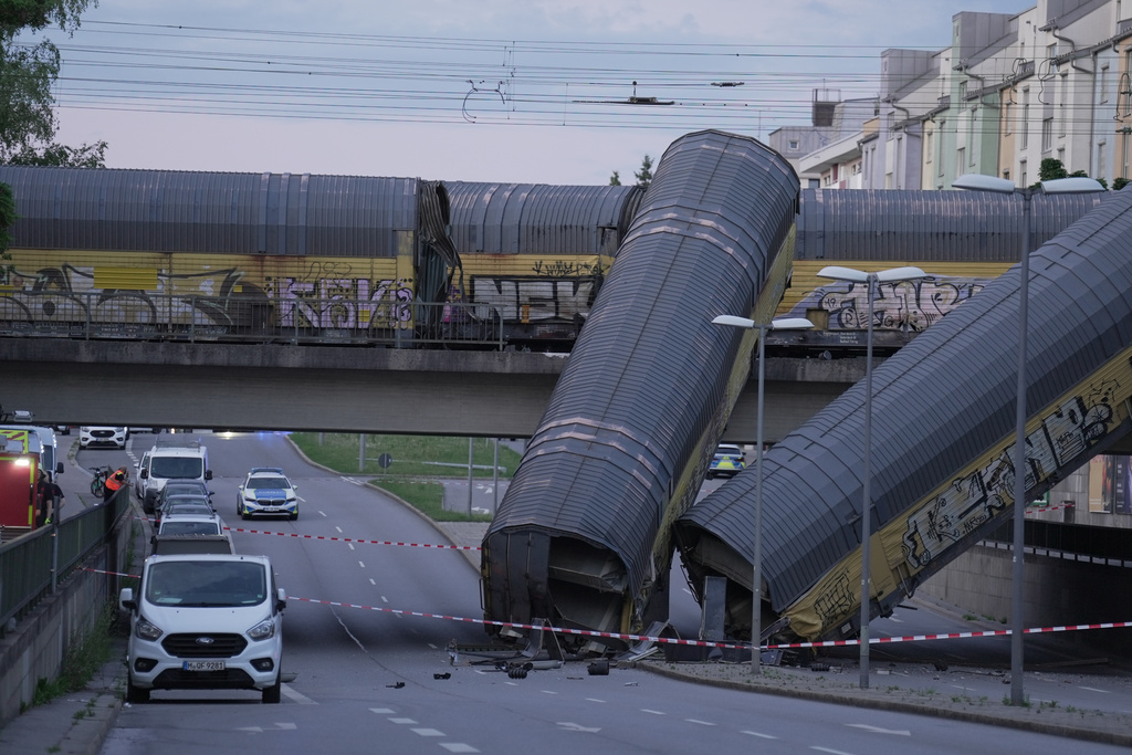 Two cars of a freight train are lying on a road after falling off a bridge in Munich, Germany, Saturday, June 20, 2026. (Ehsan Monajati/dpa via AP)