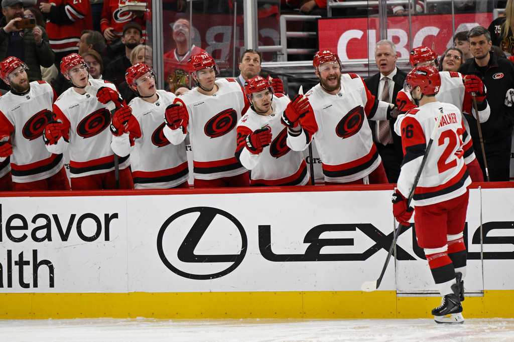 Carolina Hurricanes' Sean Walker (26) celebrates with teammates at the bench after scoring during the first period of an NHL hockey game against the Chicago Blackhawks in Chicago, Thursday, April 9, 2026. (AP Photo/Paul Beaty)