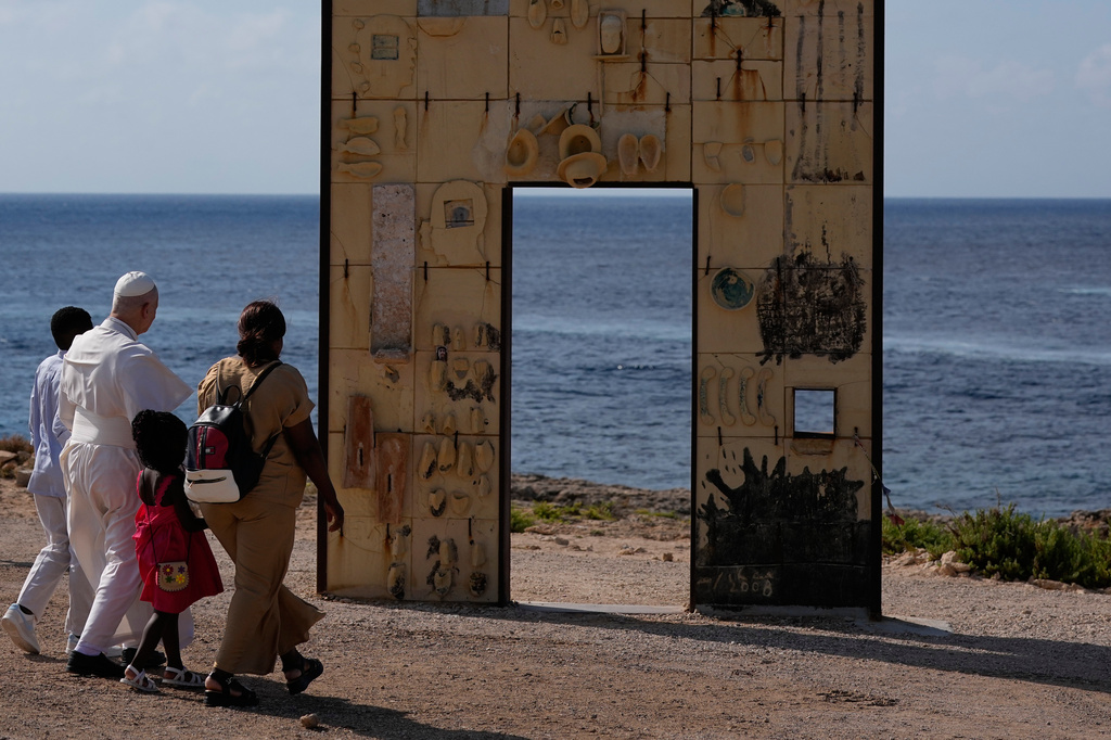 Pope Leo XIV walks together with a migrant family at the Gateway of Europe monument in Lampedusa, Sicily, southern Italy, Saturday, July 4, 2026, during a one-day pastoral visit to the island long associated with the plight of migrants crossing the Mediterranean. (AP Photo/Alessandra Tarantino)