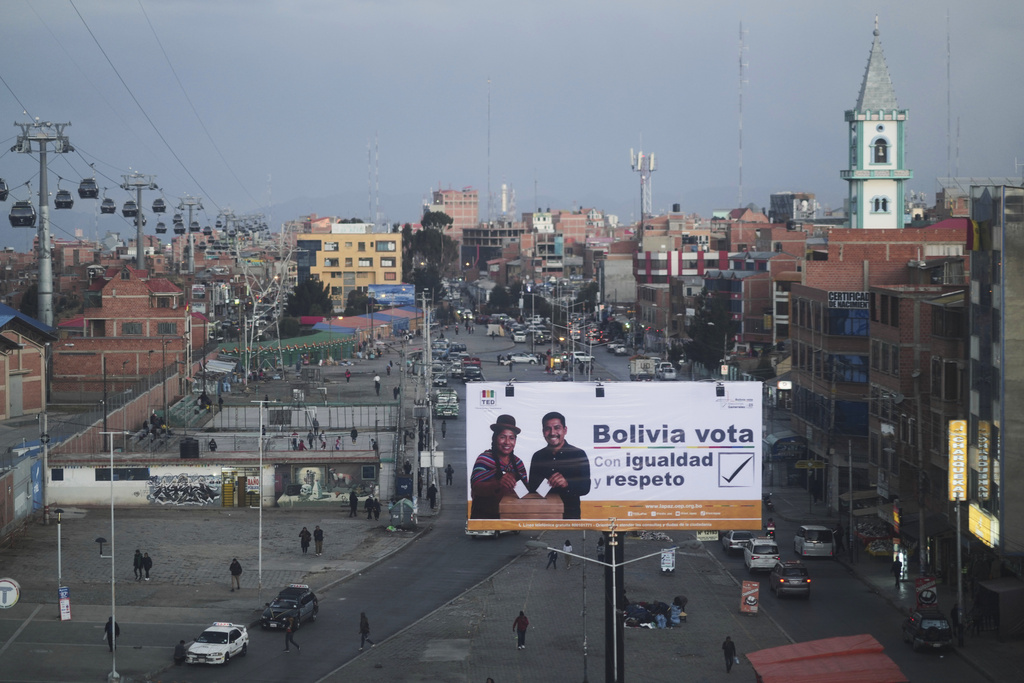 A billboard with a message that reads in Spanish; "Bolivia, vote with equality and respect", towers over pedestrians, ahead of the upcoming presidential and legislative elections in El Alto, Bolivia, Friday, Aug. 15, 2025. (AP Photo/Natacha Pisarenko)