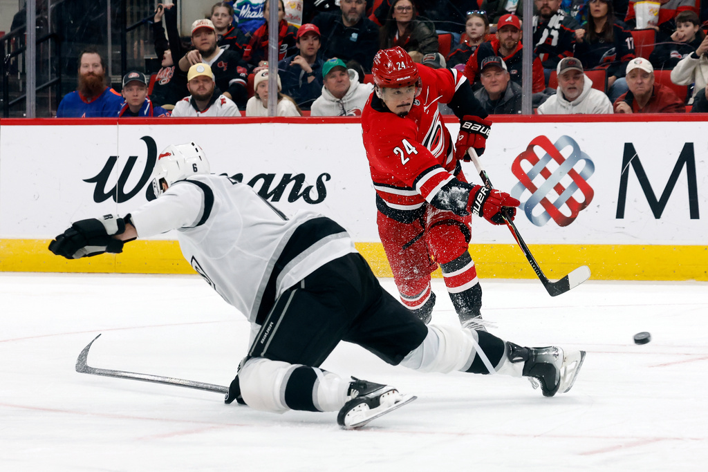 Carolina Hurricanes' Seth Jarvis (24) avoids Los Angeles Kings' Joel Edmundson, left, to shoot during the second period of an NHL hockey game in Raleigh, N.C., Sunday, Feb. 1, 2026. (AP Photo/Karl DeBlaker)