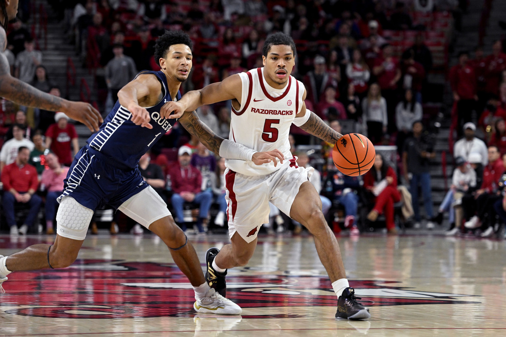 Arkansas guard Darius Acuff Jr. (5) drives past Queens guard Nasir Mann (1) during the first half of an NCAA college basketball game Tuesday, Dec. 16, 2025, in Fayetteville, Ark. (AP Photo/Michael Woods)