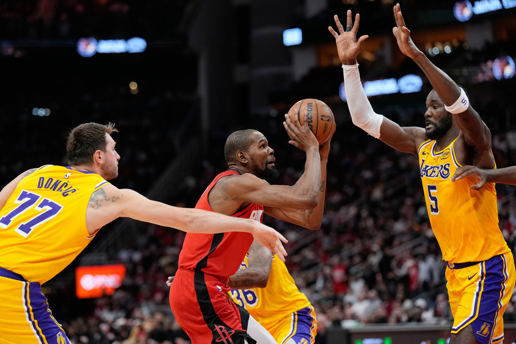 Houston Rockets' Kevin Durant, center shoots as Los Angeles Lakers' Luka Doncic (77) and Deandre Ayton (5) defend during the second half of an NBA basketball game Monday, March 16, 2026, in Houston. (AP Photo/David J. Phillip)