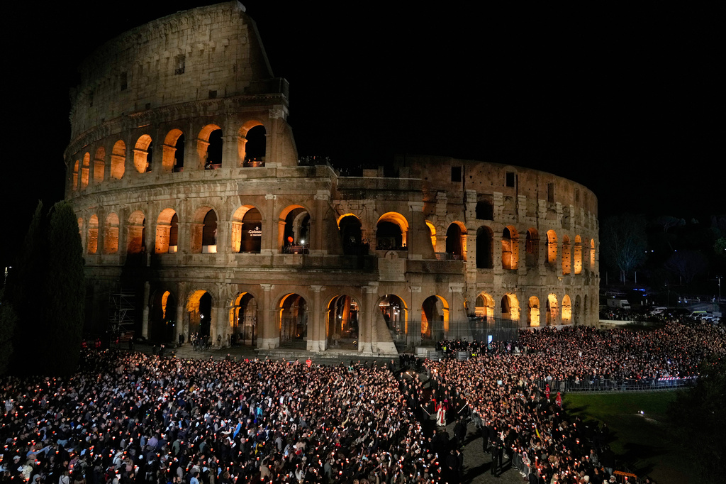 FILE - Pope Leo XIV carries wooden cross during the the torchlit Good Friday Stations of the Cross procession at the Colosseum in Rome, April 3, 2026. (AP Photo/Gregorio Borgia, File)