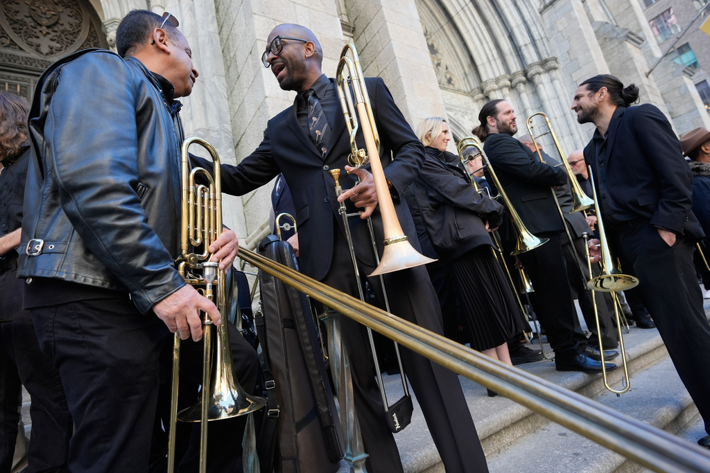 A group of musicians, primarily trombonists, socialize and warm-up pose before playing at a funeral for Willie Colon at St. Patrick's Cathedral in New York, Monday, March 9, 2026. (AP Photo/Seth Wenig)