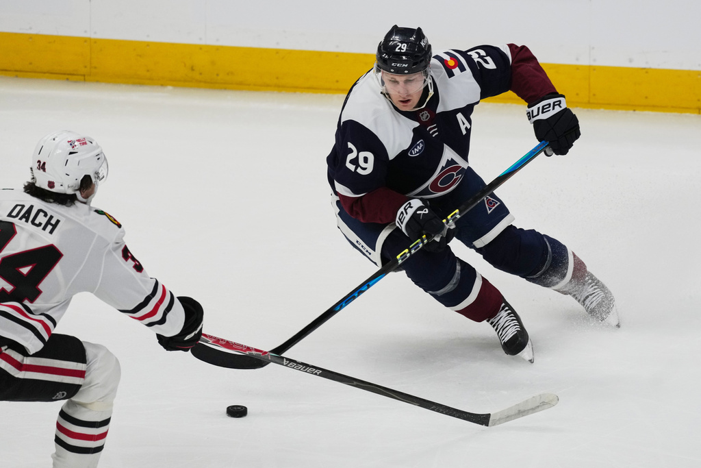 Colorado Avalanche center Nathan MacKinnon, right, looks to pass the puck as Chicago Blackhawks center Colton Dach defends in the first period of an NHL hockey game Saturday, Feb. 28, 2026, in Denver. (AP Photo/David Zalubowski)