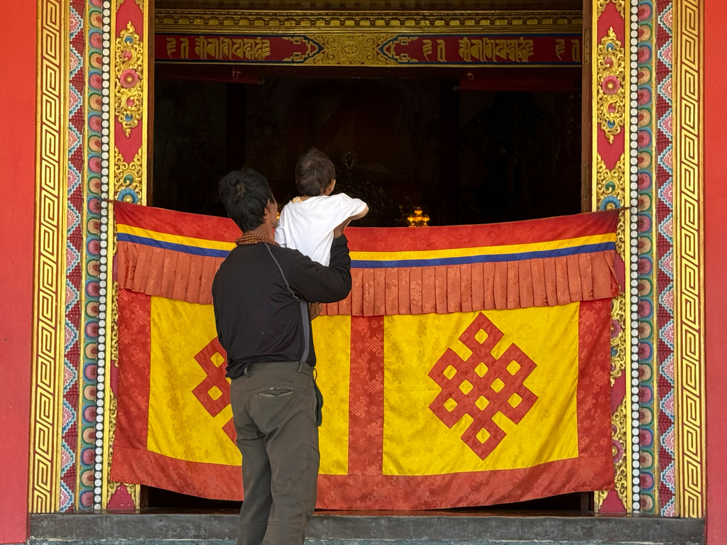 A survivor holds his child up at a monastery where survivors are seeking refuge in Kathmandu, Nepal, Monday, Aug. 31, 2026. (AP Photo/Niranjan Shrestha)