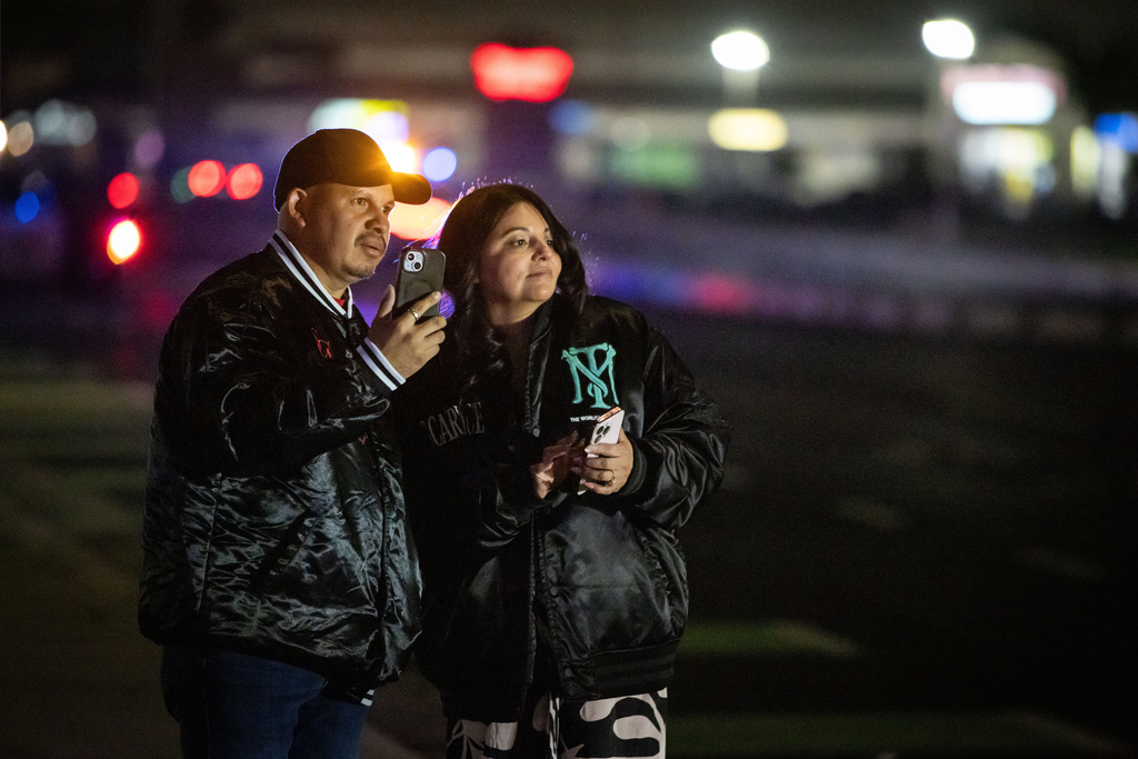 Bystanders watch at the scene of a mass shooting Saturday, Nov. 29, 2025, in Stockton, Calif. (AP Photo/Ethan Swope)