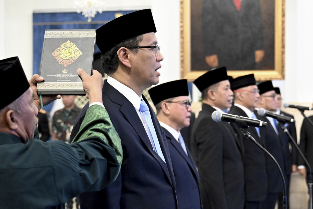 In this photo released by the Press and Media Bureau of the Indonesian Presidential Palace, an Islamic cleric holds a holy book of Quran over the head of the new Finance Minister Purbaya Yudhi Sadewa as he takes his oath with other newly appointed ministers and vice ministers during a swearing in ceremony at the State Palace in Jakarta, Indonesia, Monday, Sept. 8, 2025. (Cahyo Bruri Sasmito, Indonesian Presidential Palace via AP)