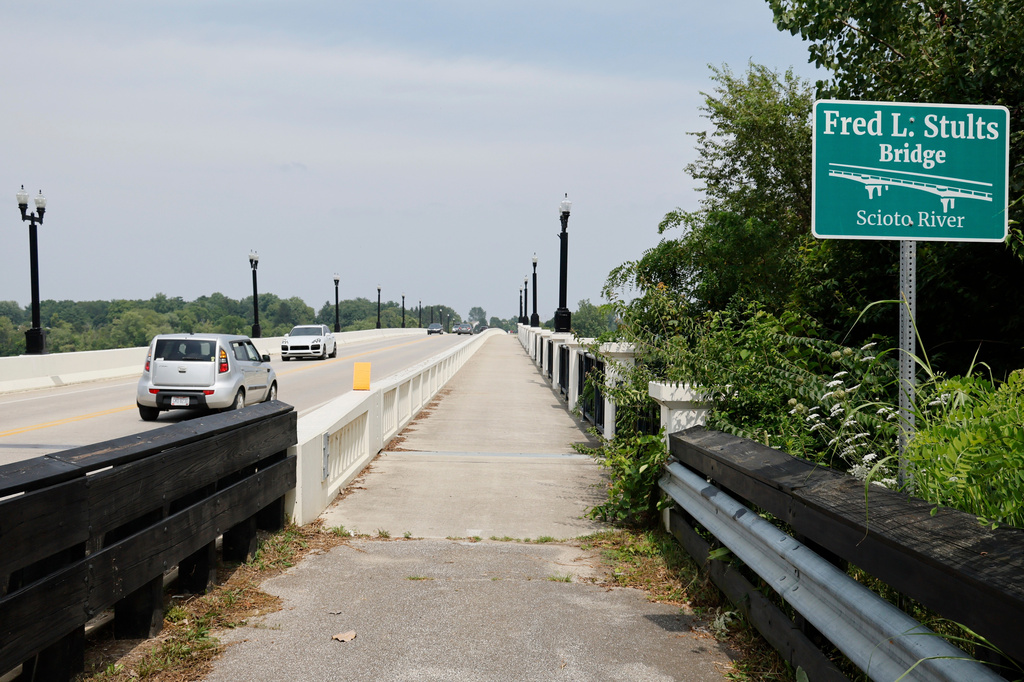 Cars drive on the Fred L, Stults Bridge over the Scioto River near where multiple people died after several of them went into the water to help another person who was struggling to swim Monday, July 20, 2026, in Powell, Ohio. (AP Photo/Jay LaPrete)