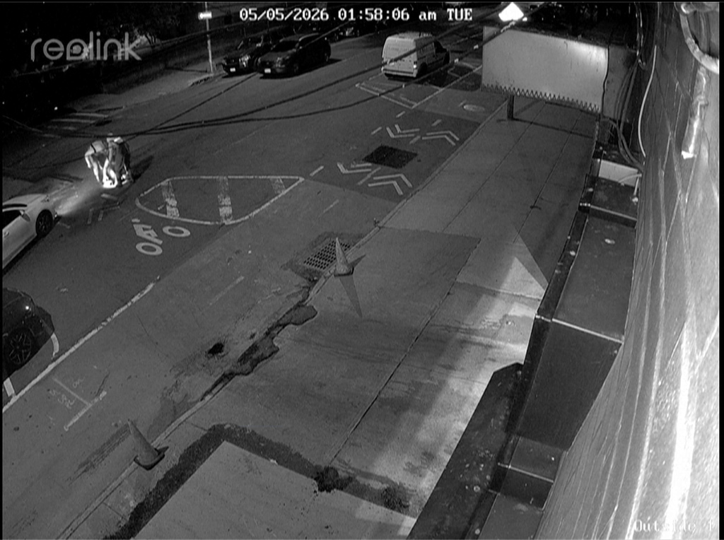 In this image from a surveillance video provided by AKI AUTO CARE, three people descend into a sewer on a street in New York, on May 5, 2026. (AKI AUTO CARE via AP)