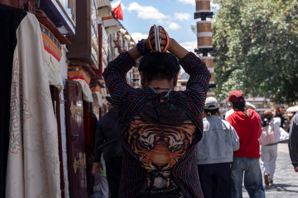 A pilgrim performs full body prostrations along Barkhor Street in Lhasa in western China's Tibet Autonomous Region on Tuesday, July 21, 2026, as seen during a government organized visit for foreign journalists. (AP Photo/Ng Han Guan)