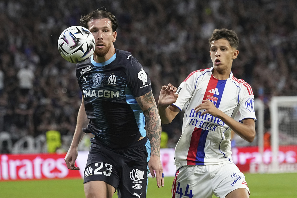 Marseille's Pierre-Emile Hojbjerg, left, challenges for the ball with Lyon's Khalis Merah during the French League One soccer match between Lyon and Marseille, in Decines, outside Lyon, France, Sunday, Aug. 31, 2025. (AP Photo/Laurent Cipriani)