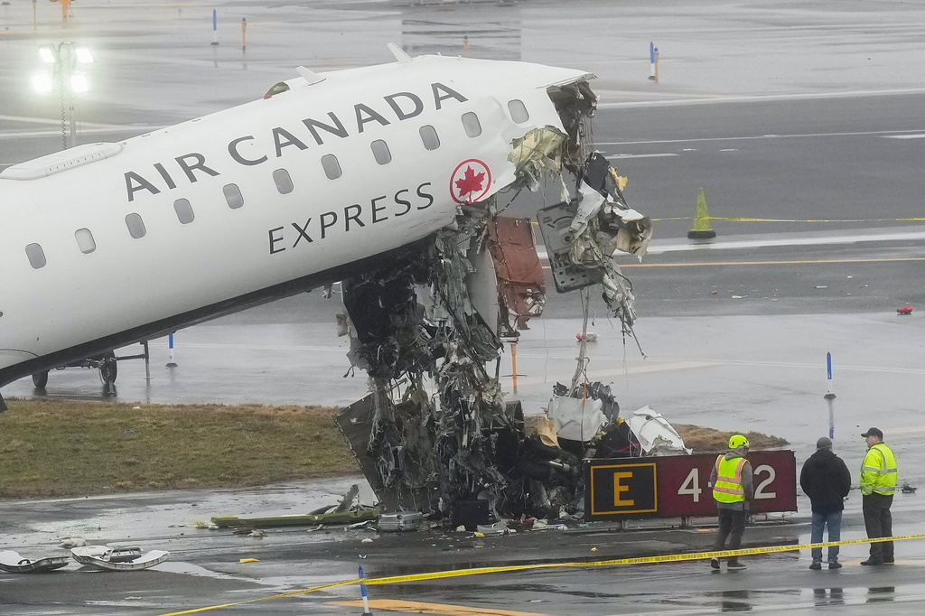 FILE - Officials investigate the site, Monday, March 23, 2026, where an Air Canada jet came to rest after colliding with a Port Authority firetruck at LaGuardia Airport, shortly after landing Sunday night in New York. (AP Photo/Seth Wenig, file)