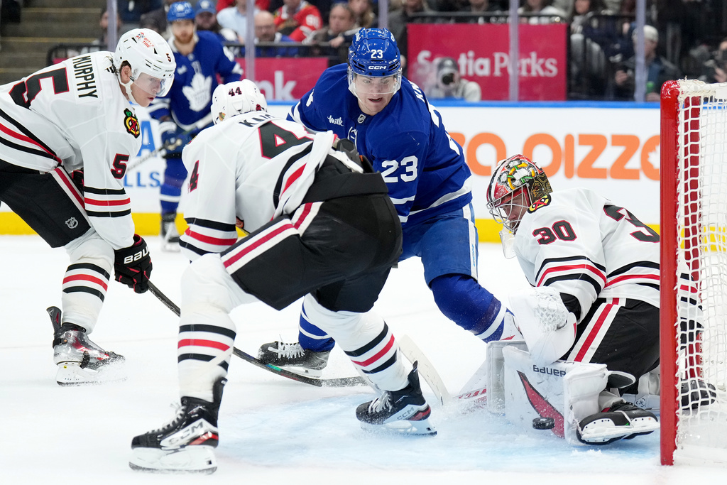 Chicago Blackhawks goaltender Spencer Knight (30) makes a save on Toronto Maple Leafs forward Matthew Knies (23) during second period NHL hockey action in Toronto, Tuesday, Dec. 16, 2025. (Nathan Denette/The Canadian Press via AP)