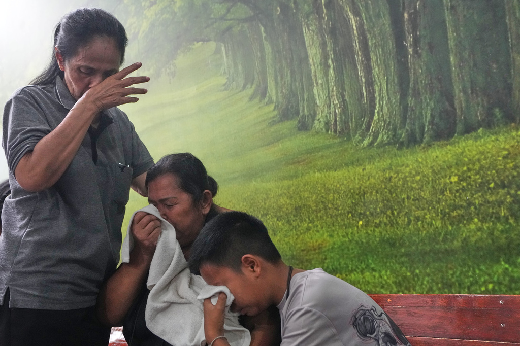 Relatives of a victim in a music bar fire cry while receiving the victim's body at a police hospital in Bangkok, Thailand, Tuesday, July 14, 2026. (AP Photo/Sakchai Lalit)