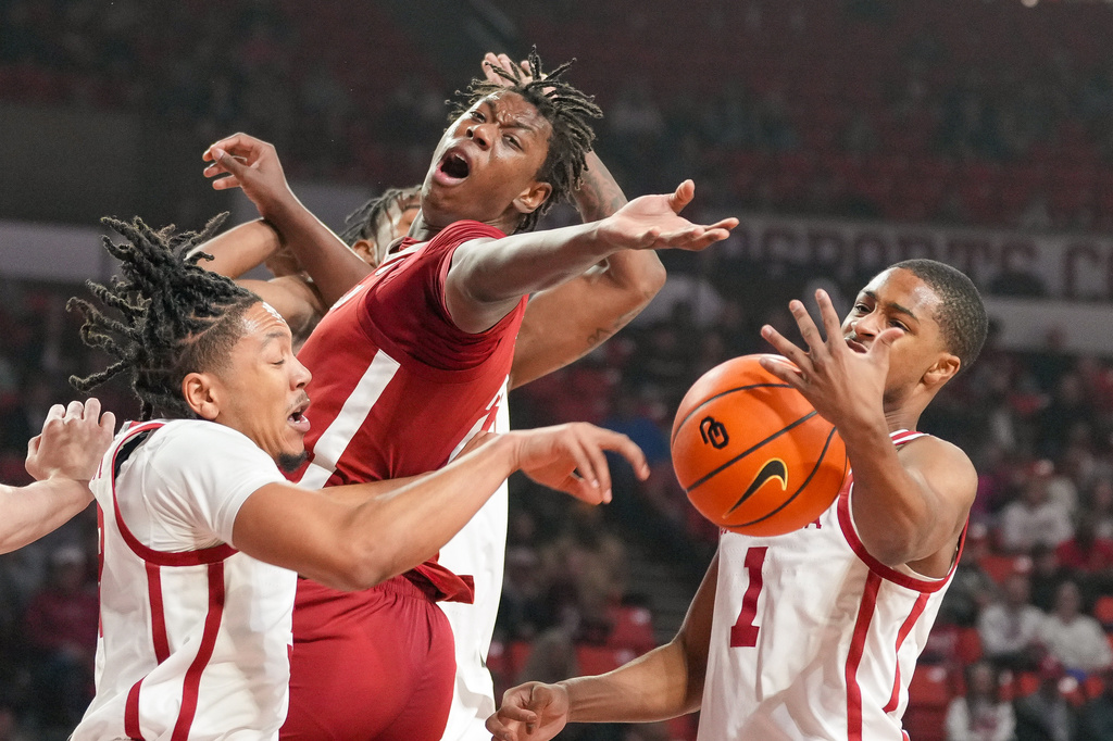 Alabama forward Aiden Sherrell, middle, goes after a rebound over Oklahoma guards Nijel Pack, left, and Xzayvier Brown, right, during the first half of an NCAA college basketball game, Saturday, Jan. 17, 2026, in Norman, Okla. (AP Photo/Kyle Phillips)