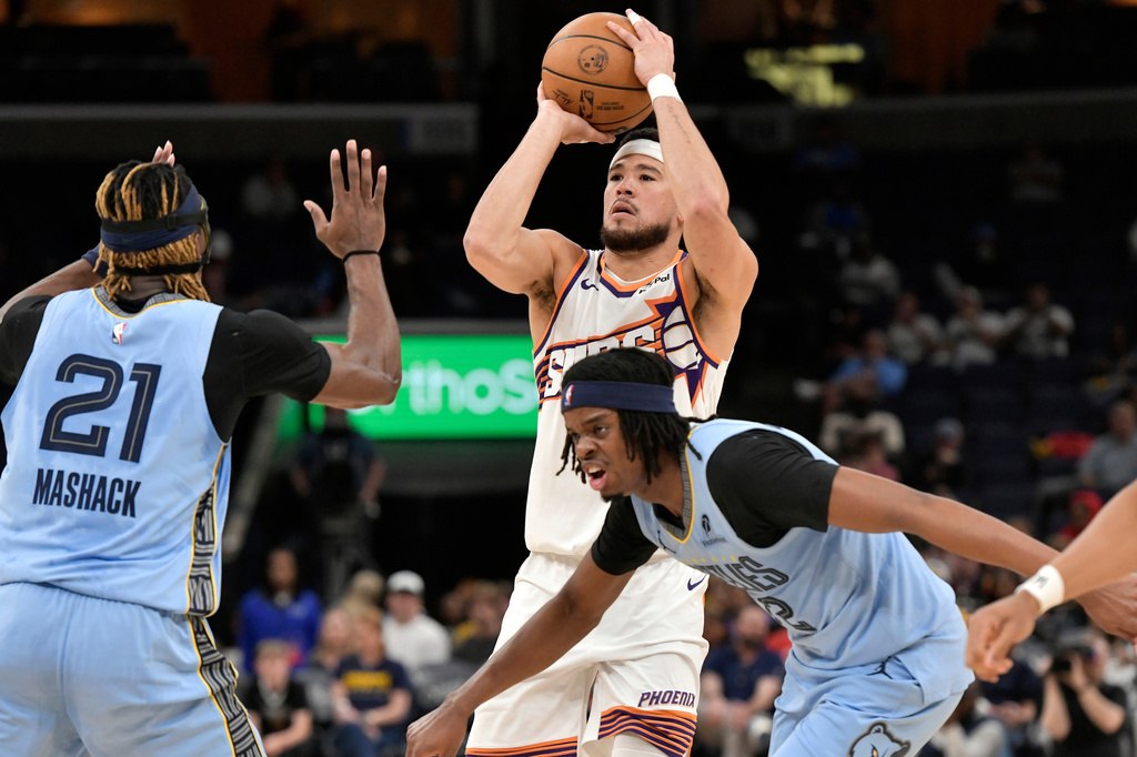 Phoenix Suns guard Devin Booker shoots over Memphis Grizzlies guard Jahmai Mashack (21) and forward Adama Bal, lower right, in the second half of an NBA basketball game Monday, March 30, 2026, in Memphis, Tenn. (AP Photo/Brandon Dill)