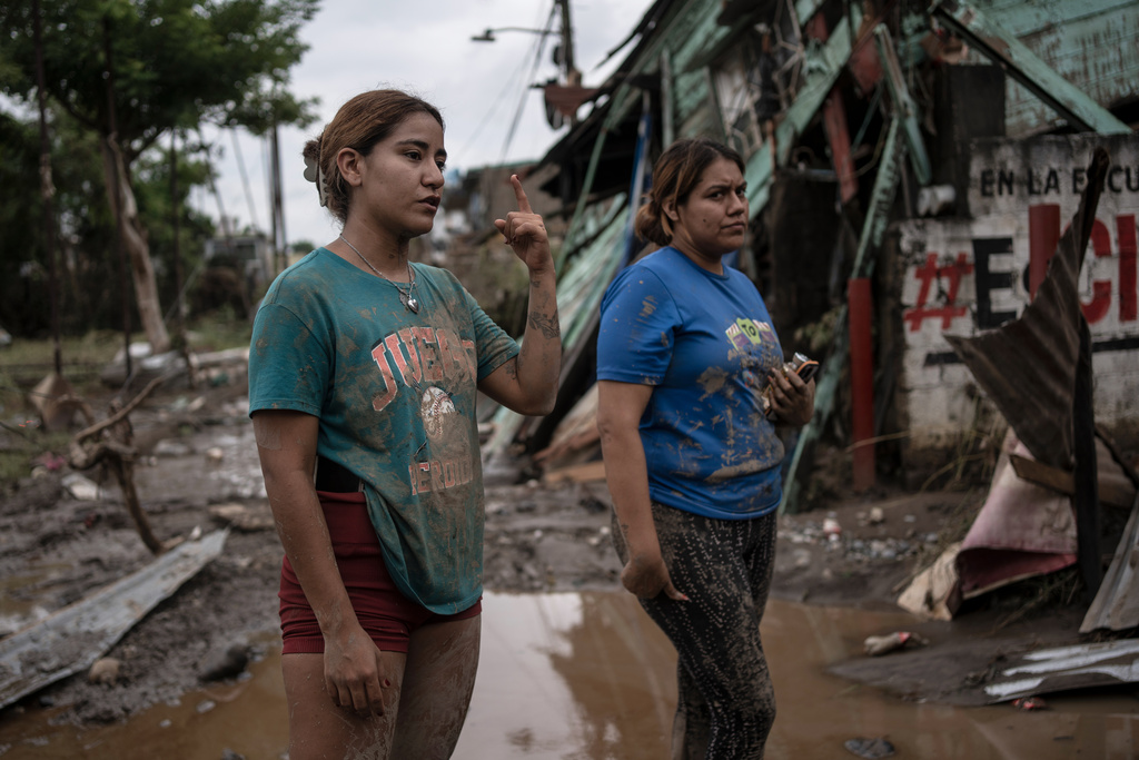 Relatives of Gustavo Azuara, who died during a flood, stand outside their damaged house after heavy rainfall in Poza Rica, Veracruz state, Mexico, Saturday, Oct. 11, 2025. (AP Photo/Felix Marquez)