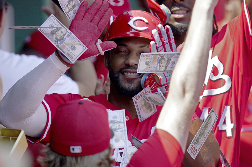 Teammates shower Cincinnati Reds' Miguel Andujar with play money in the dugout after his three-run home run during the third inning of a baseball game against the Pittsburgh Pirates, Sunday, Aug. 10, 2025, in Pittsburgh. (AP Photo/Matt Freed)
