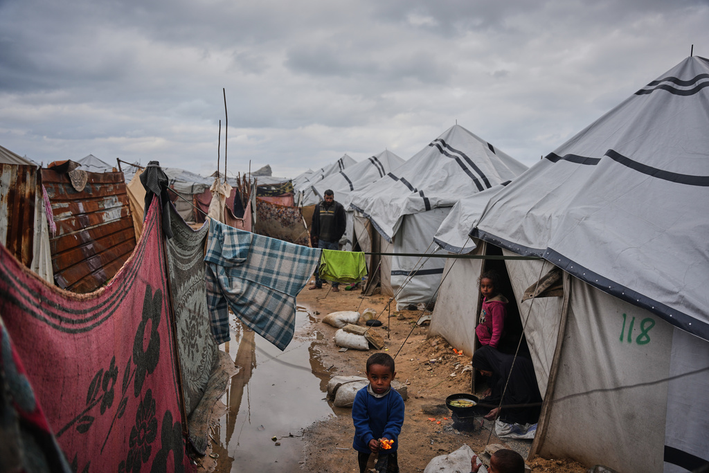 FILE - Nanaa Abu Jari cooks outside her tent after it was flooded by rainwater in Nuseirat, central Gaza Strip, Friday, Jan. 2, 2026. (AP Photo/Abdel Kareem Hana, File)