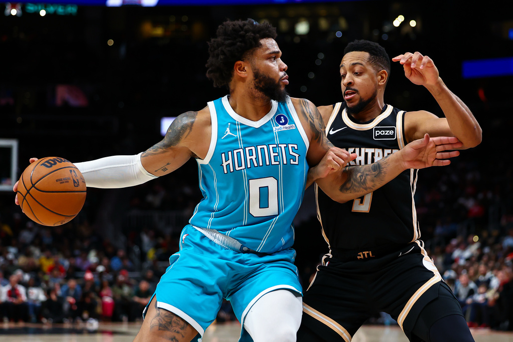 Charlotte Hornets forward Miles Bridges (0) dribbles against Atlanta Hawks guard CJ McCollum, right, during the first half of an NBA basketball game, Saturday, Feb. 7, 2026, in Atlanta. (AP Photo/Colin Hubbard)