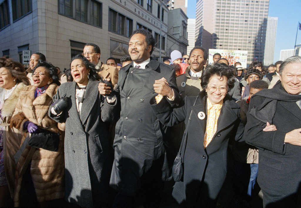 FILE - Coretta Scott King holds hands while singing with the Rev. Jesse Jackson and Christine Farris, the sister of Dr. Martin Luther King, Jr., as they parade on Peachtree Street in Atlanta on Monday, Jan. 19, 1987 to honor King's birthday. At left in Mrs. Alveda king Beall and at right is Lupita Aquino Kashiwahara. (AP Photo/Charles Kelly, File)