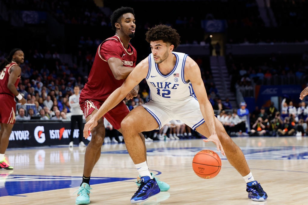 Duke forward Cameron Boozer (12) drives against Florida State forward Chauncey Wiggins during the first half of an NCAA college basketball game in the quarterfinals of the Atlantic Coast Conference tournament in Charlotte, N.C., Thursday, March 12, 2026. (AP Photo/Nell Redmond)
