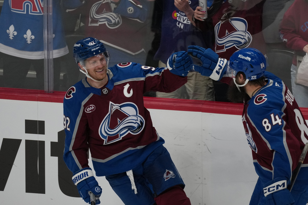 Colorado Avalanche defenseman Brent Burns, right, congratulates left wing Gabriel Landeskog after his goal against the Calgary Flames in the first period of an NHL hockey game Monday, March 30, 2026, in Denver. (AP Photo/David Zalubowski)