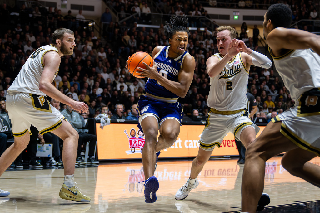 Washington guard Quimari Peterson (0) drives through the defense of Purdue center Oscar Cluff, left, and guard Fletcher Loyer (2) during the first half of an NCAA college basketball game, Wednesday, Jan. 7, 2026, in West Lafayette, Ind. (AP Photo/Doug McSchooler)