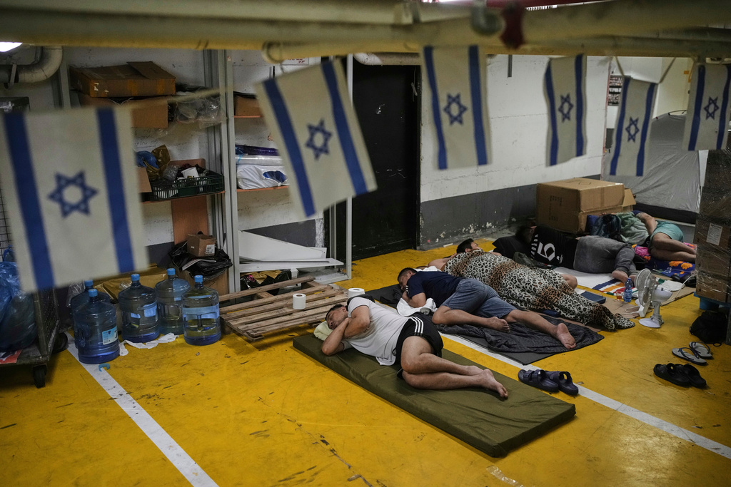 FILE - People rest and as they take shelter in an underground parking garage as a precaution against possible Iranian missile attacks, in Tel Aviv, Israel, Tuesday, June 24, 2025. (AP Photo/Ohad Zwigenberg, File)