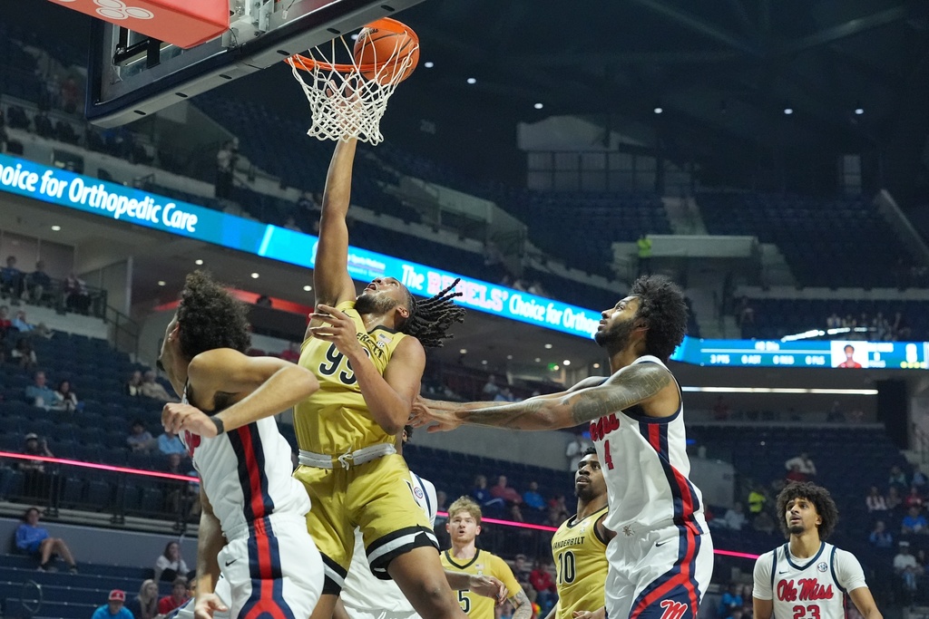 Vanderbilt forward Devin McGlockton (99) makes a layup between two Mississippi players during the first half of an NCAA college basketball game, Tuesday, Mar. 3, 2026, in Oxford, Miss. (AP Photo/Rogelio V. Solis)