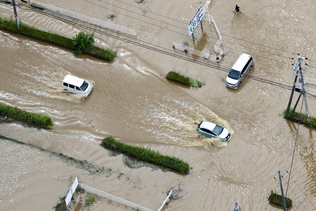 Cars make their way through flooded road after heavy rain in Oamishirasato, Chiba prefecture, Japan, Friday, Aug. 14, 2026. (Kota Endo/Kyodo News via AP)