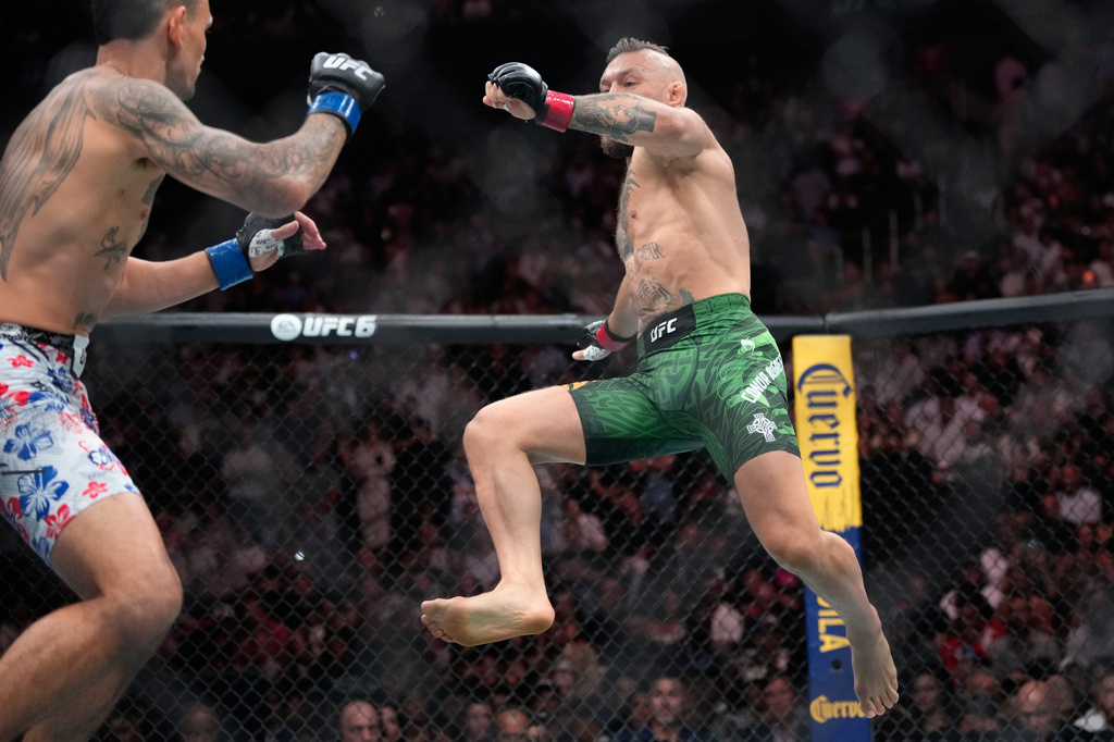 Conor McGregor, right, jumps into the air for a kick as he fights Max Holloway in a welterweight fight at the UFC 329 mixed martial arts event Saturday, July 11, 2026, in Las Vegas. (AP Photo/John Locher)