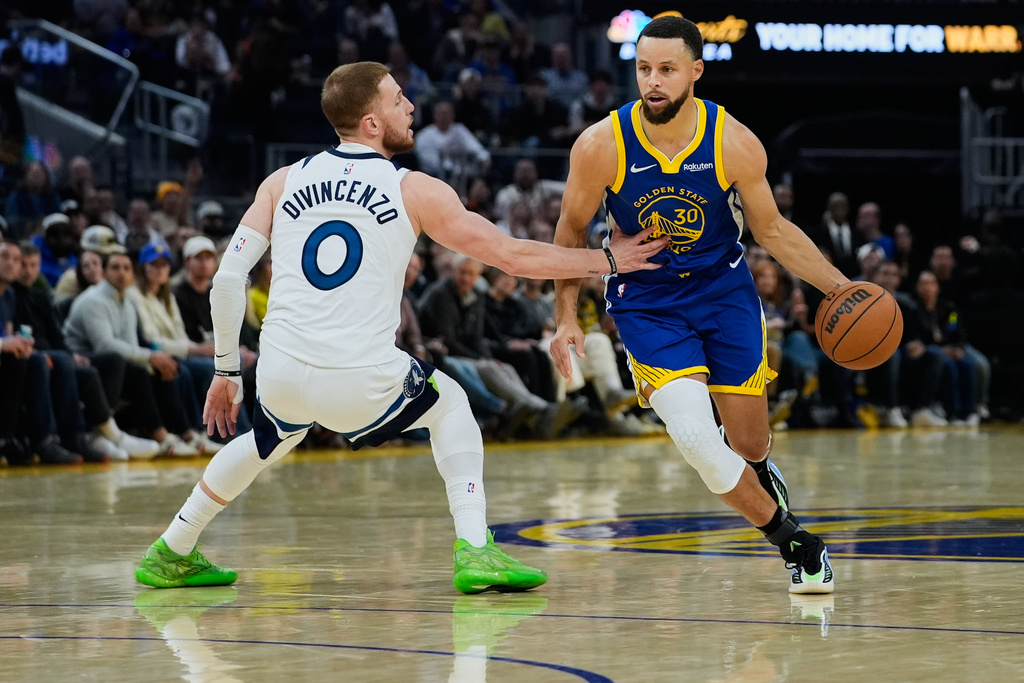 Golden State Warriors guard Stephen Curry (30) moves the ball while defended by Minnesota Timberwolves guard Donte Divincenzo (0) during the first half of an NBA basketball game, Friday, Dec. 12, 2025, in San Francisco. (AP Photo/Godofredo A. Vásquez)