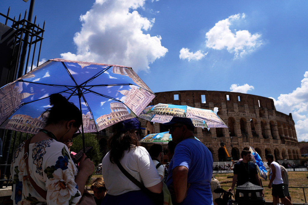 FILE - Tourists use umbrellas to shelter from the heat as they line up for a tour of the Forum in Rome, on Tuesday, July 22, 2025. (AP Photo/Gregorio Borgia, File)