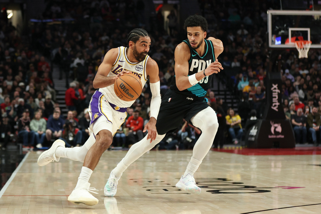 Gabe Vincent (izquierda), de los Lakers de Los Ángeles, se dirige a la canasta mientras Toumani Camara, de los Trail Blazers de Portland, defiende durante la primera mitad de un juego de baloncesto de la NBA, el sábado 17 de enero de 2026, en Portland, Oregón. (AP Photo/Amanda Loman)
