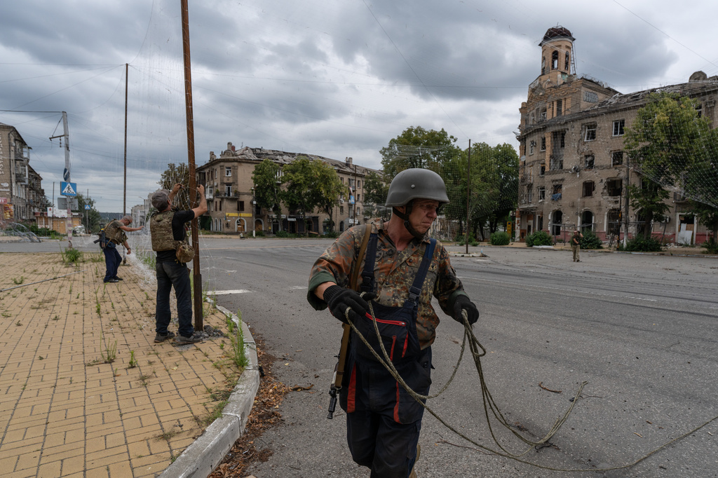 In this photo provided by Ukraine's 93rd Kholodnyi Yar Separate Mechanized Brigade press service and taken Saturday, July 25, 2026, Ukrainian servicemen repair the damaged anti-drone net in the frontline town of Druzhkivka, Donetsk region, Ukraine. (Iryna Rybakova/Ukraine's 93rd Mechanized Brigade via AP)