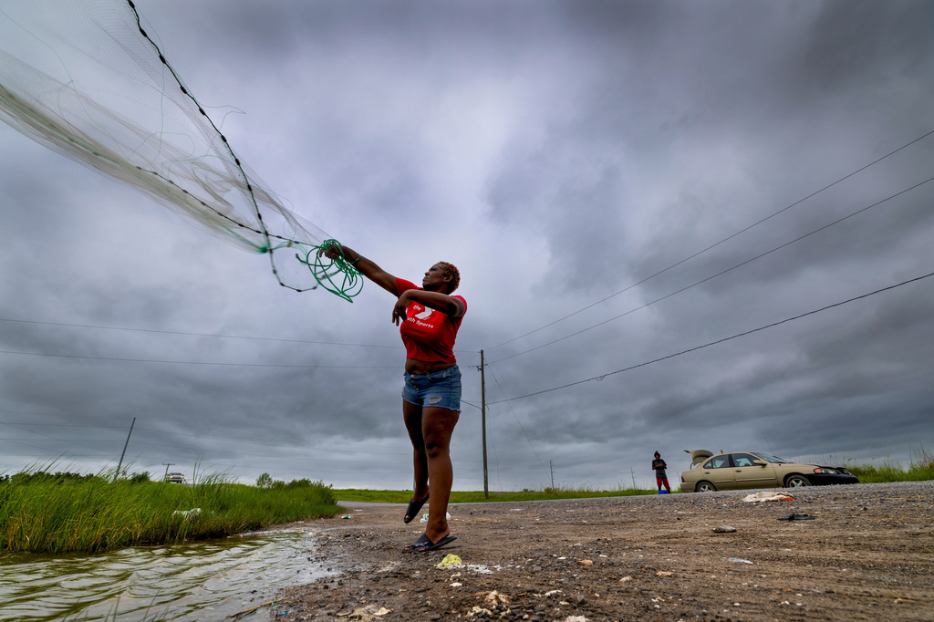 With skies darkening ahead of Tropical Storm Bertha, Latia Ancar practices her casting while she and a friend wait for the storm-driven tidal surge about 50 miles south of New Orleans on Wednesday, July 22, 2026, hoping it will bring more fish. (Chris Granger/The Times-Picayune/The New Orleans Advocate via AP)