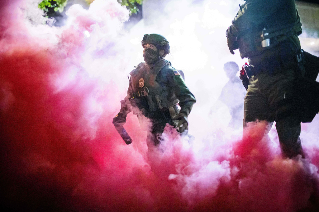 Police and federal officers throw gas canisters to disperse protesters near a U.S. Immigration and Customs Enforcement facility in Portland, Ore. on Sunday, Oct. 5, 2025. (AP Photo/Ethan Swope)