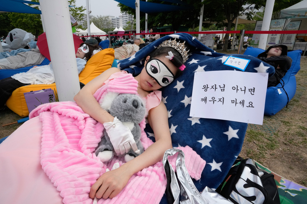 A participant takes a nap during the 2026 Hangang Nap Competition at Yeouido Hangang Park in Seoul, South Korea, Saturday, May 2, 2026. The writing reads "Don't wake me up unless it's a prince." (AP Photo/Ahn Young-joon)