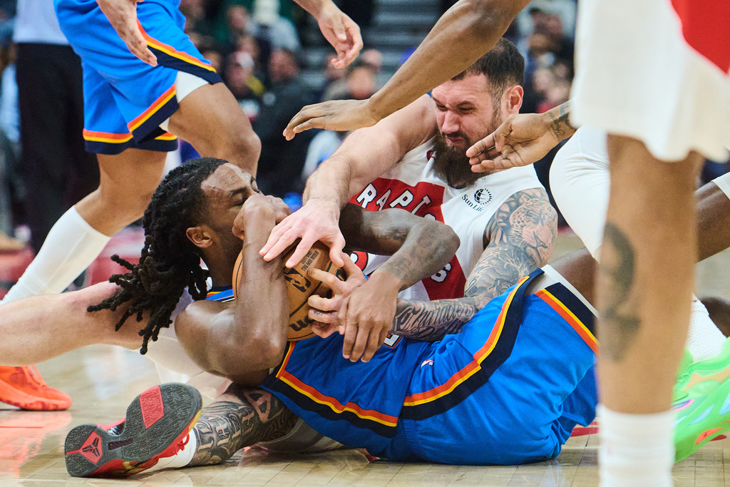Oklahoma City Thunder's Cason Wallace, front, and Toronto Raptors' Sandro Mamukelashvili battle for the ball during the first half of an NBA basketball game in Toronto, on Tuesday, Feb. 24, 2026. (Sammy Kogan/The Canadian Press via AP)