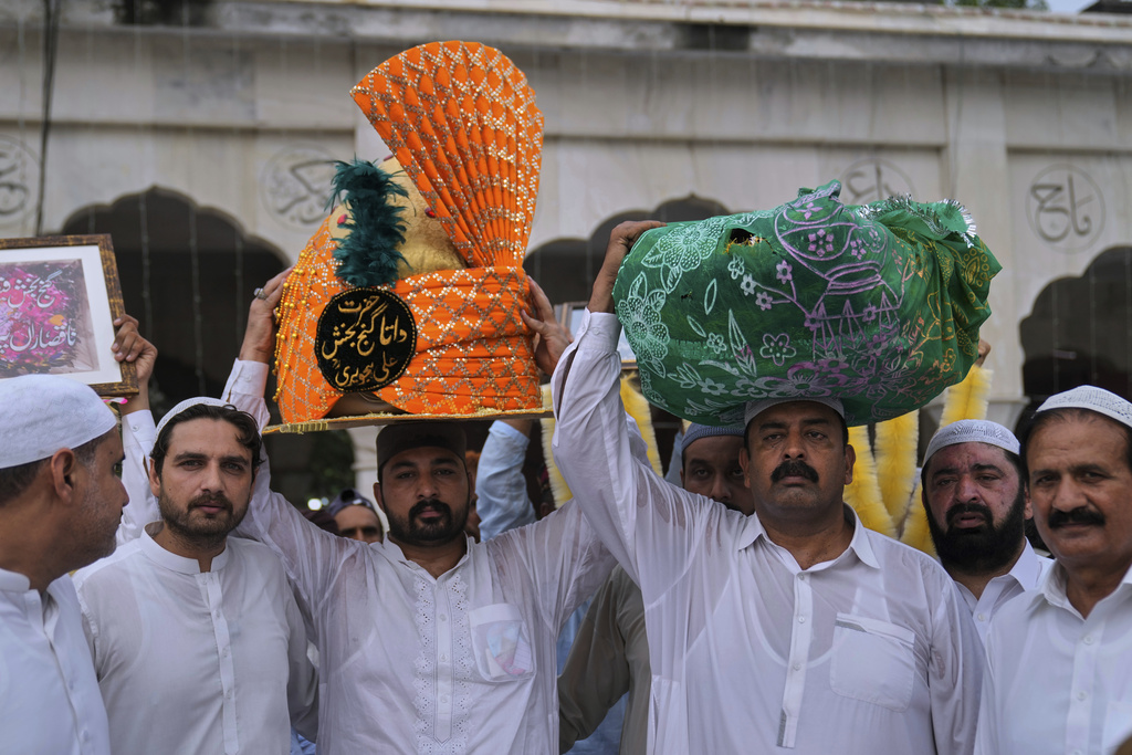 Devotees carry a big turban and bundle of garland as they arrive to attend celebrations of the three-day annual festival or 'Urs' of mystic and scholar Hazrat Ali Hajveri, popularly known as Data Ganj Bakhsh at his shrine, in Lahore, Pakistan, Friday, Aug. 15, 2025. (AP Photo/K.M. Chaudary)