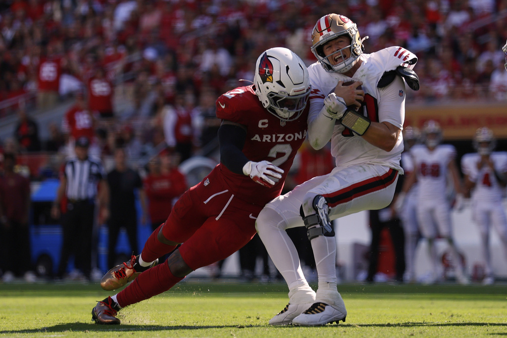 San Francisco 49ers quarterback Mac Jones, right, is tackled by Arizona Cardinals linebacker Mack Wilson during the second half of an NFL football game Sunday, Sept. 21, 2025, in Santa Clara, Calif. (AP Photo/Sergio Estrada)