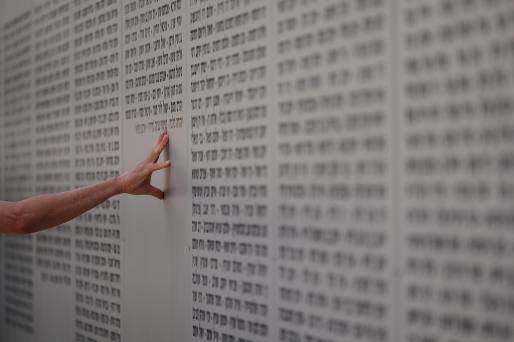 A man touches the wall with names of fallen soldiers during Israel's annual Memorial Day for the soldiers who died in the nation's conflicts and victims of nationalistic attacks at the Armored Corps memorial site in Latrun, Israel, Tuesday, April 21, 2026. (AP Photo/Ariel Schalit)
