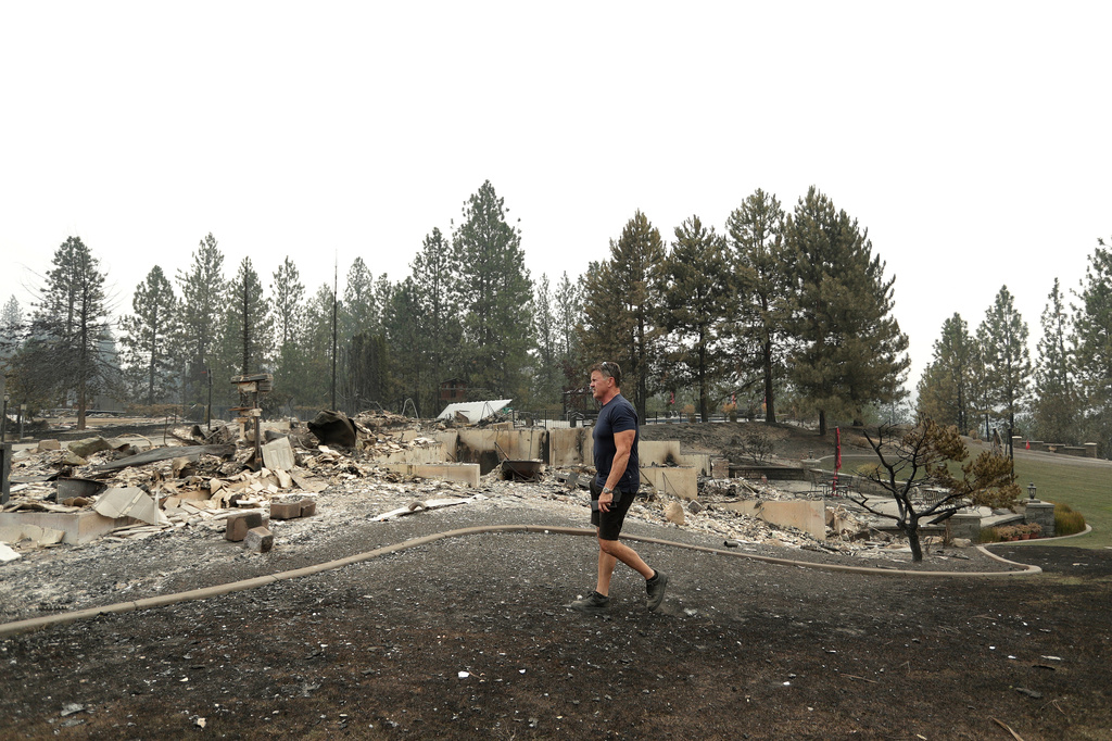Dan Munson walks in the backyard of his home on W. TIffany Ave. after it burned in a wildfire, Sunday, Aug. 2, 2026, in Spokane, Wash. (AP Photo/Young Kwak)