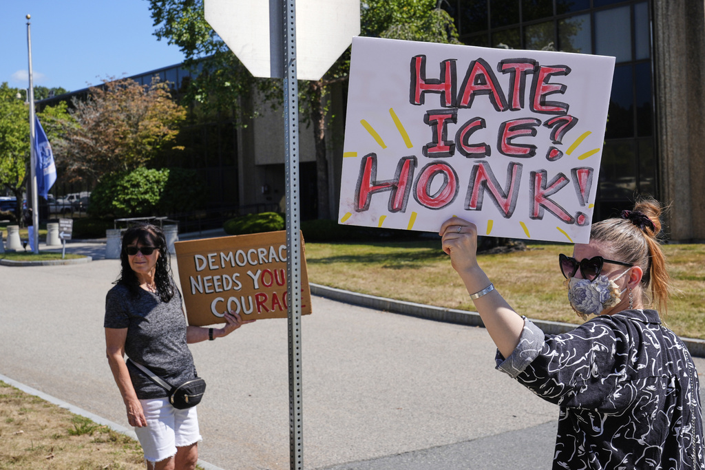 Protesters picket outside the U.S. Immigration and Customs Enforcement regional field office, at rear, Thursday, Sept. 11, 2025, in Burlington, Mass. (AP Photo/Charles Krupa)