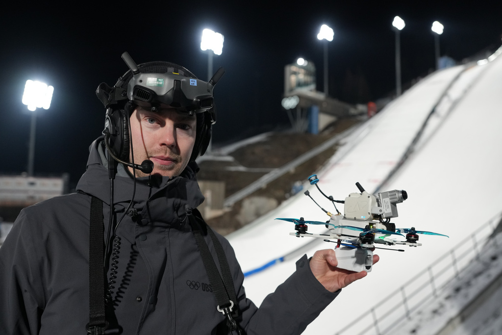 Drone pilot Jonas Sundal, from Canada, holds one of the drones being flown at the ski jumping venue during the 2026 Winter Olympics, in Predazzo, Italy, Tuesday, Feb. 10, 2026. (AP Photo/Evgeniy Maloletka)